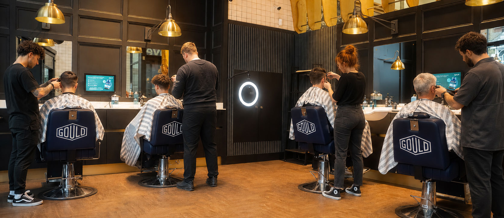 Premium barber shop with screens at every chair and clients mid-cut