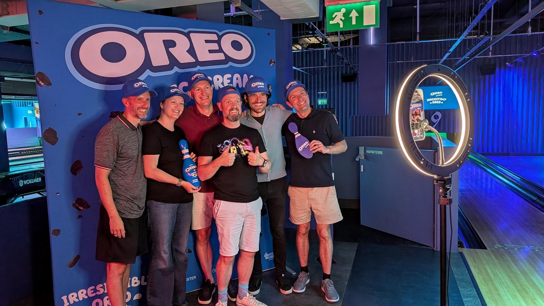 Team posing in front of an Oreo Ice Cream backdrop at the bowling event